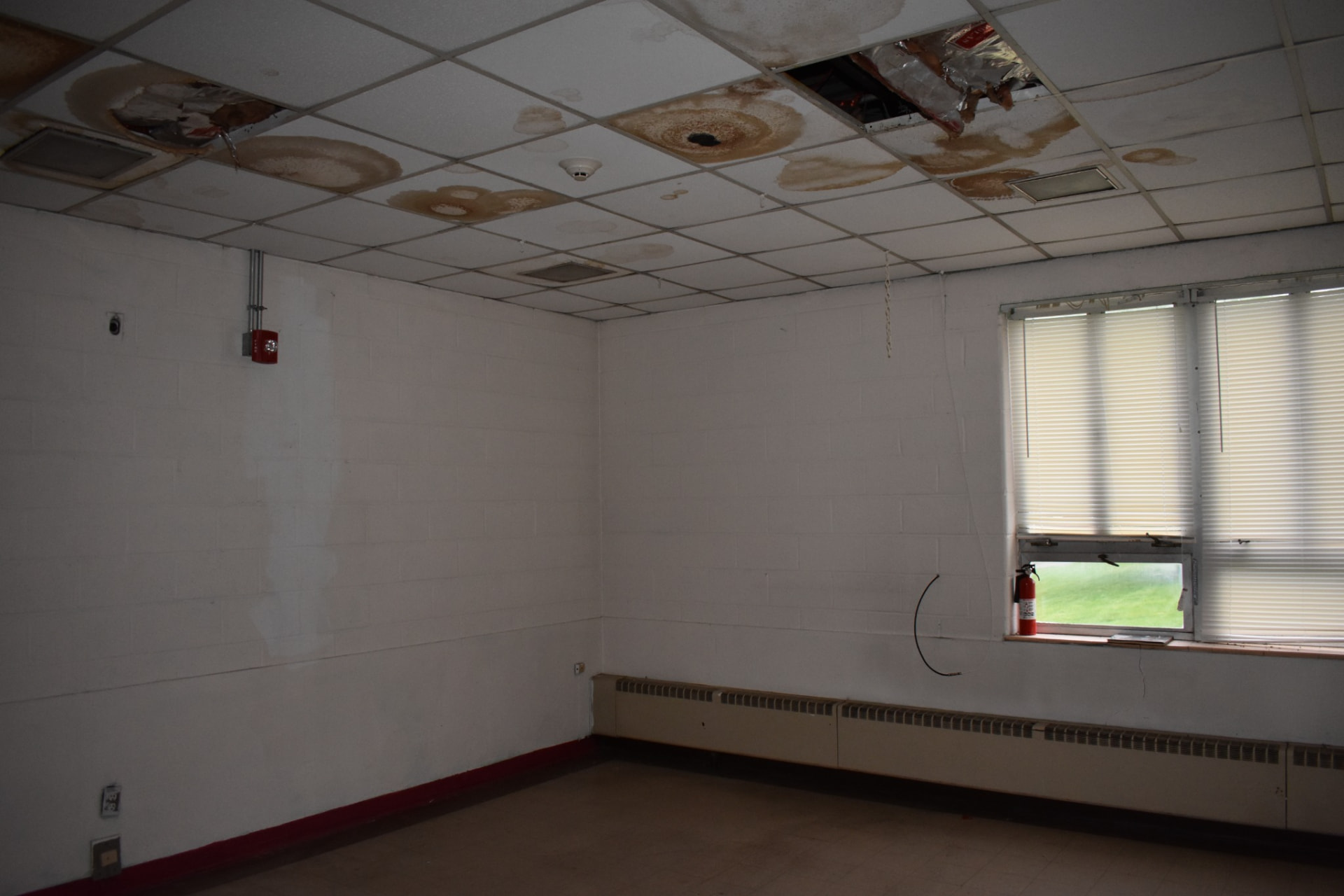 Institutional room with heavily water-stained and collapsed ceiling tile, documented before work