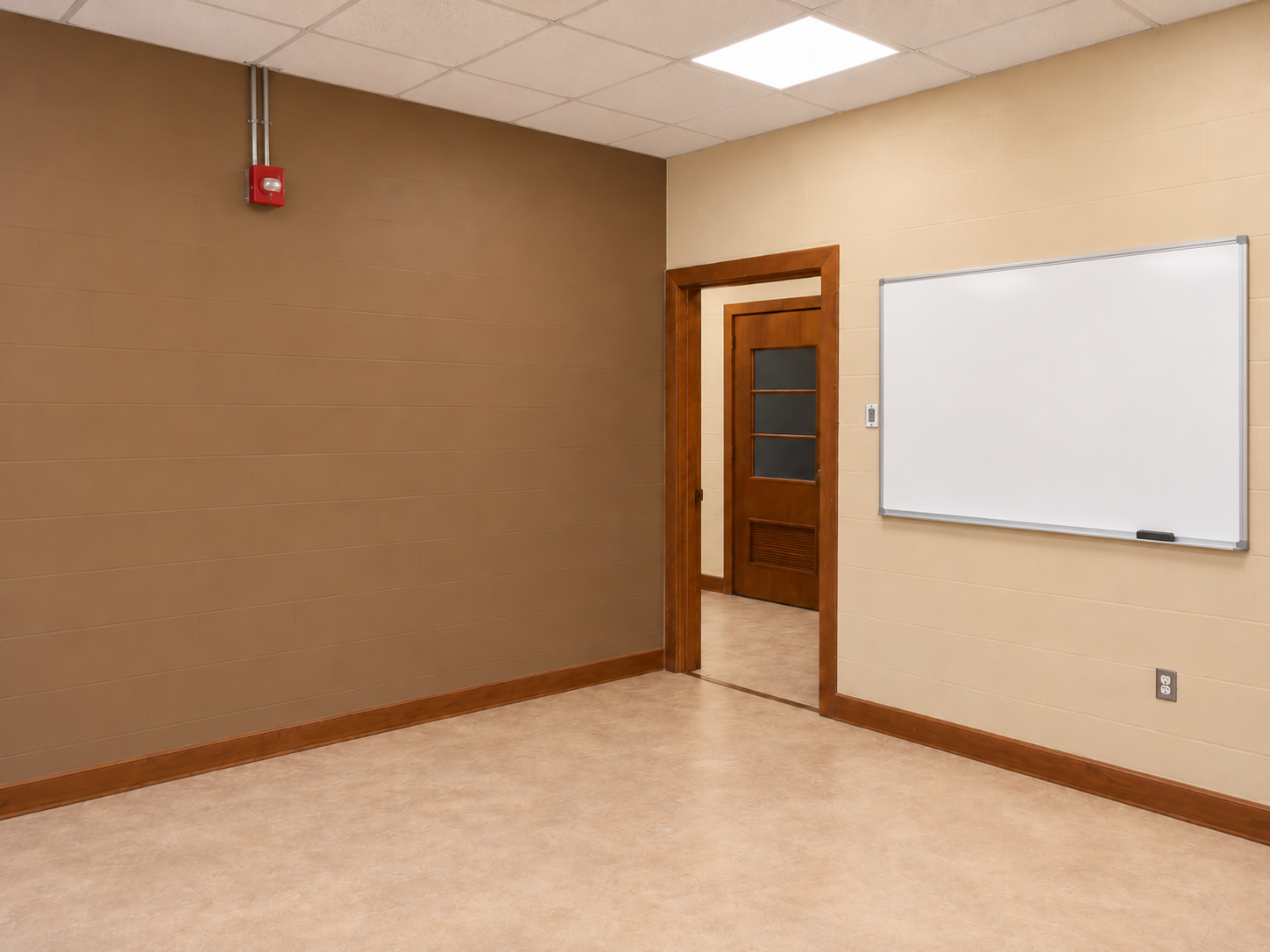 Classroom with a brown left accent wall, tan right wall with a large whiteboard, wood doorway, wood-brown baseboards, red alarm and light flooring