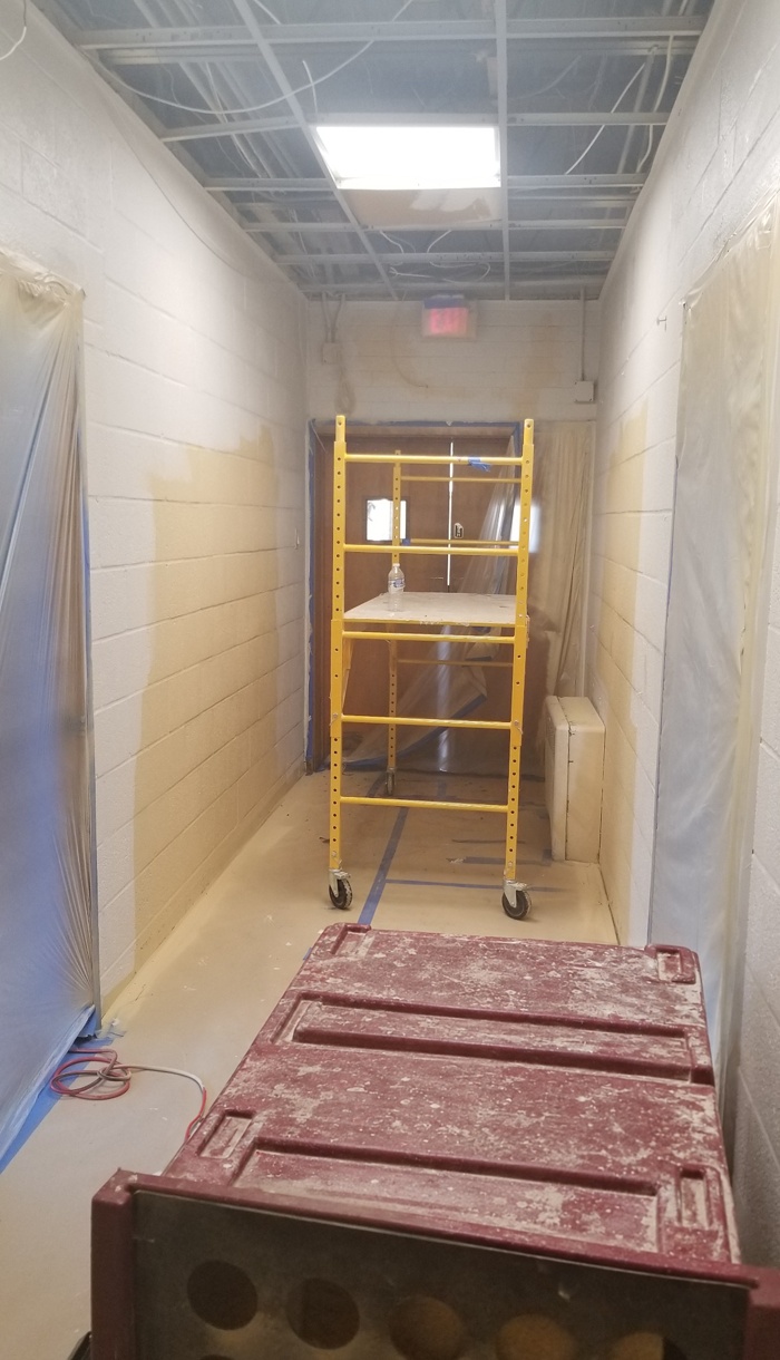 Hallway wall finish work around a scaffold and protected doorways