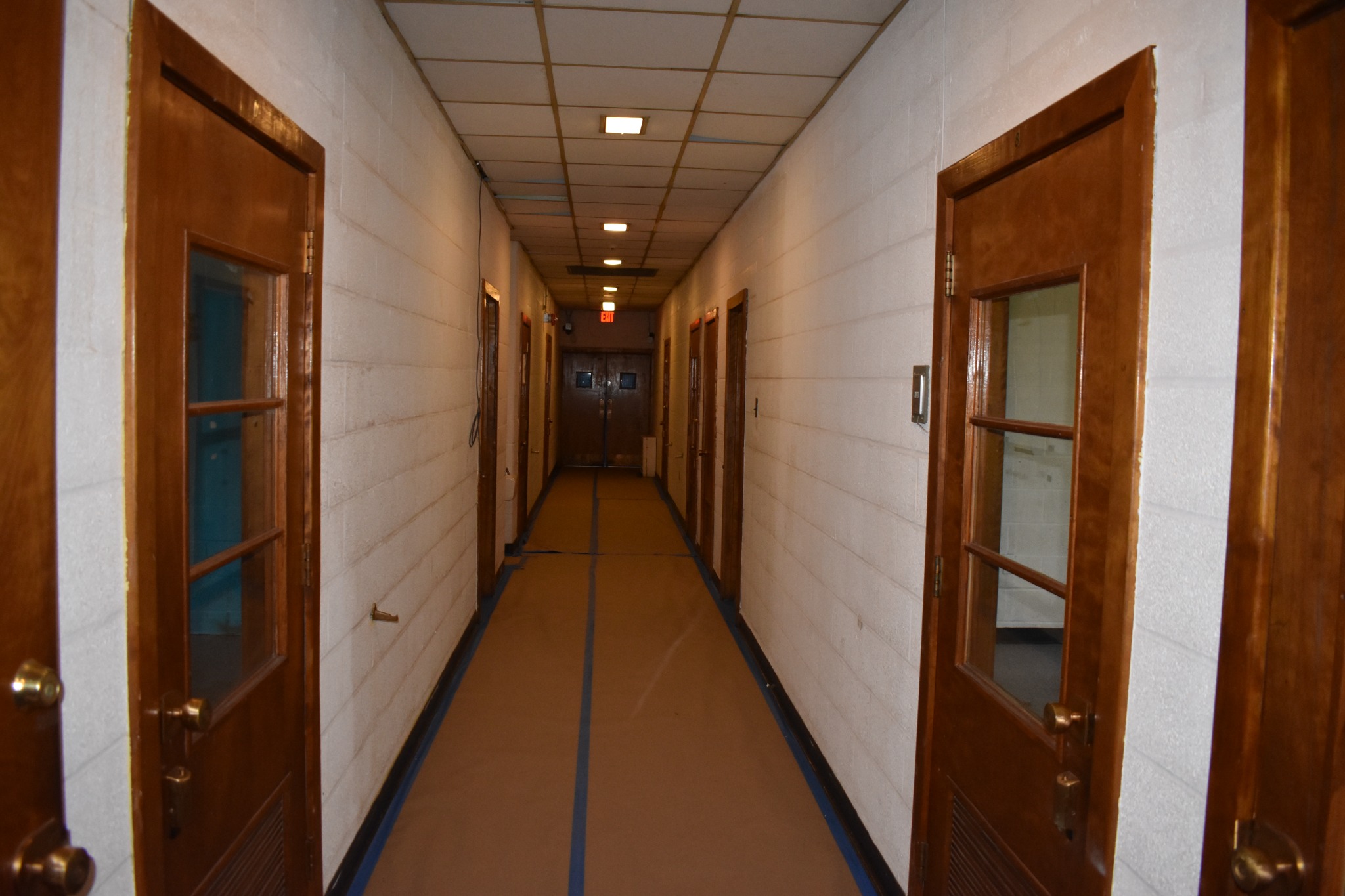 Opposite hallway view with protected flooring and existing ceiling panels