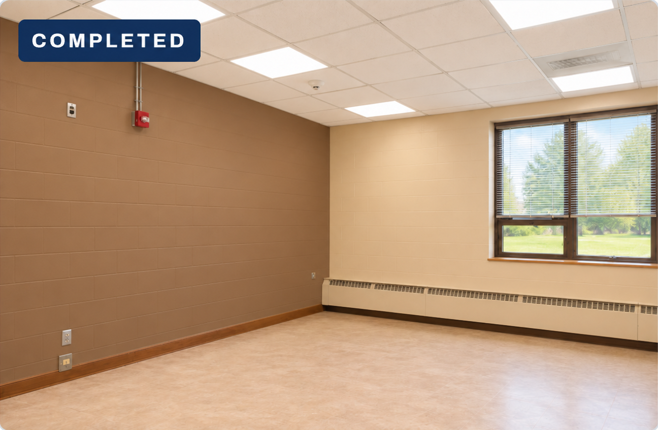 Classroom with a warm-brown left accent wall, tan window wall, bronze window frames, light flooring and ceiling lighting