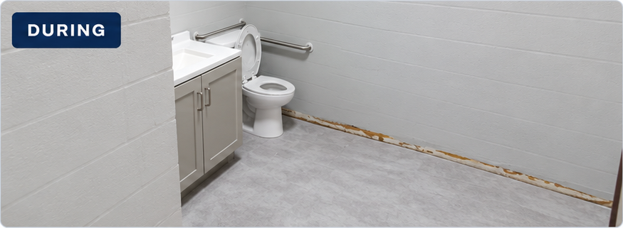 Daycare restroom during work, with vanity and toilet installed and unfinished wall-base areas visible