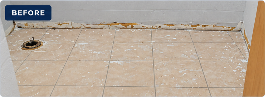 Daycare restroom with fixtures removed, tile floor and damaged base of wall