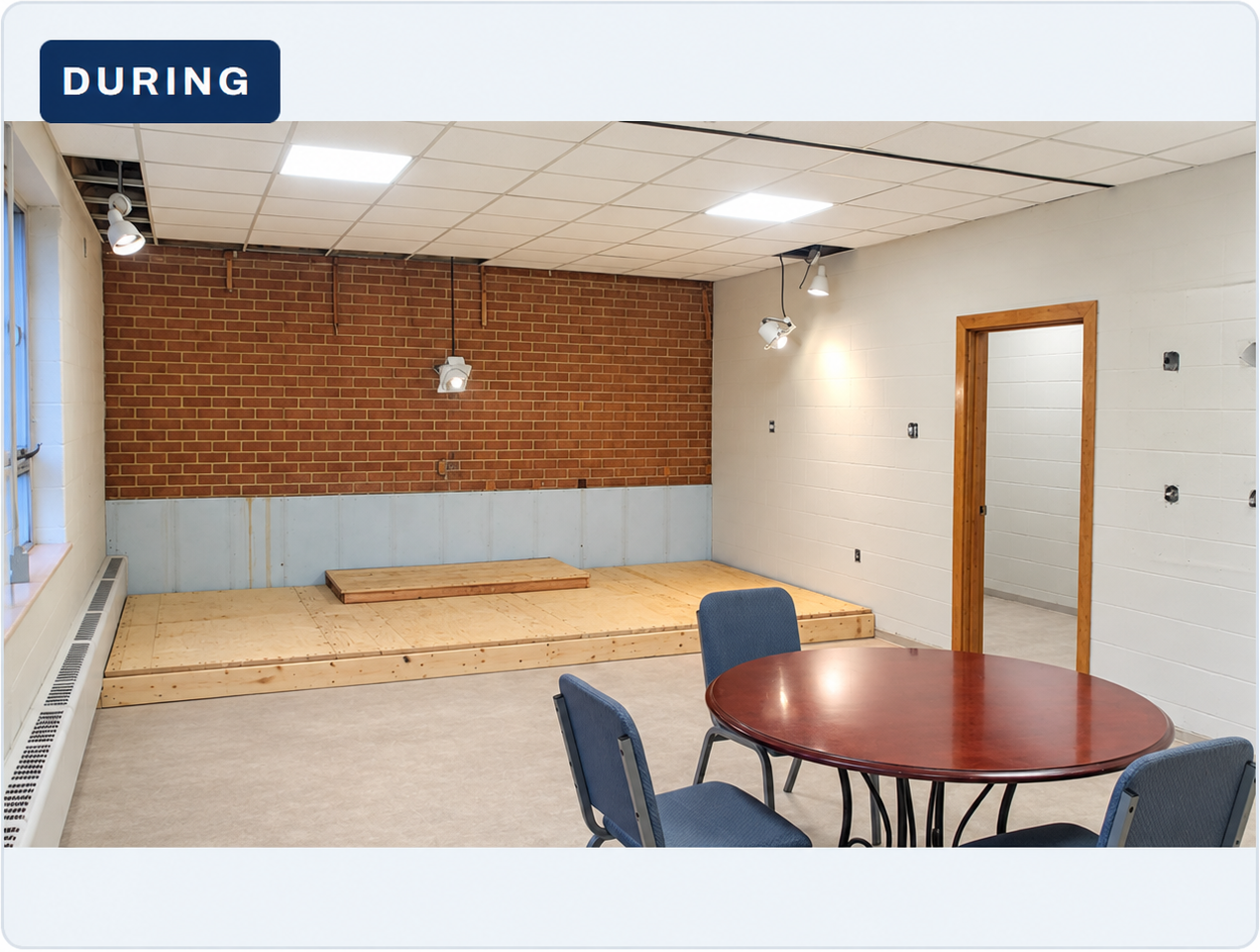 Stage and rear wall exposed during renovation, with work equipment in the room