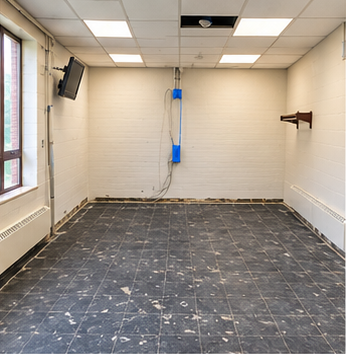 Room preparation view with dark existing floor surface, block walls and suspended ceiling